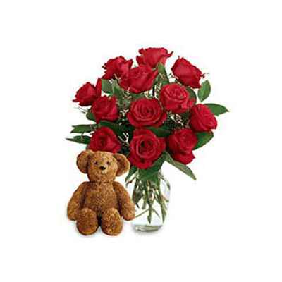 red roses in vase and a cuddly teddy bear